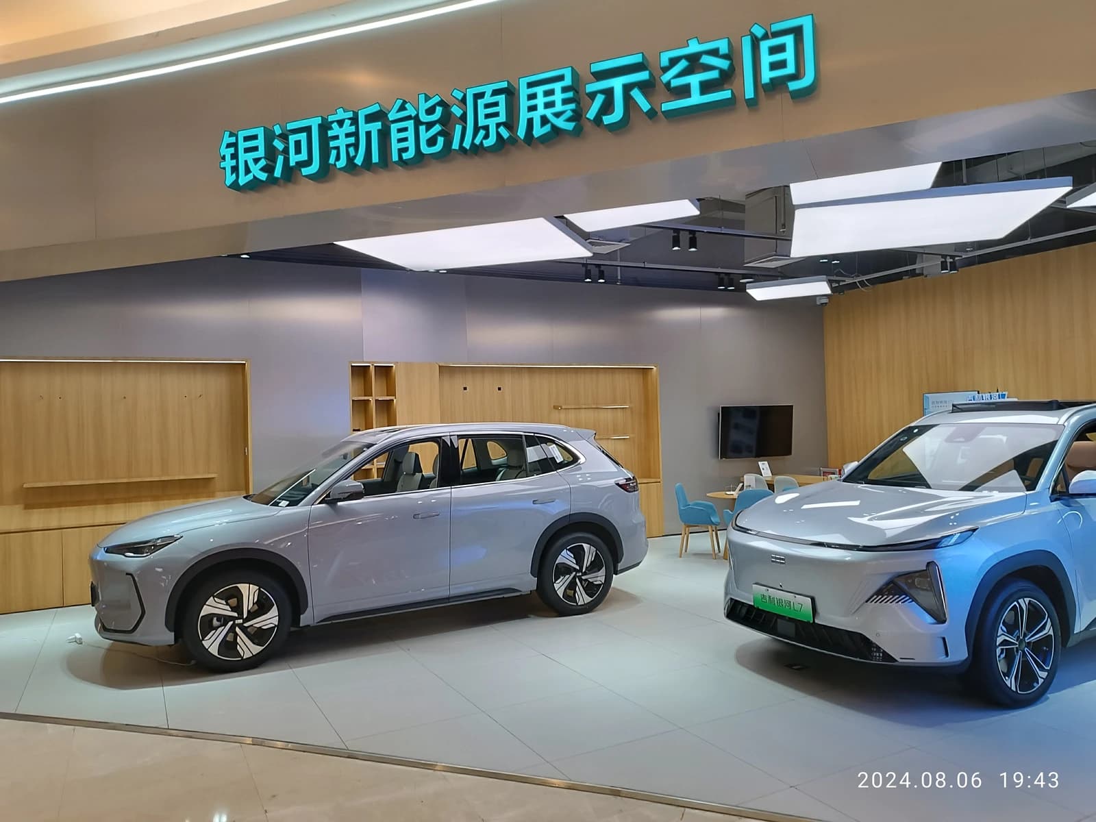Two Geely Galaxy new energy vehicles on display inside a car showroom.