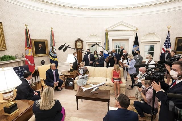 Donald Trump sits in the Oval Office with the Governor of Arizona and others.