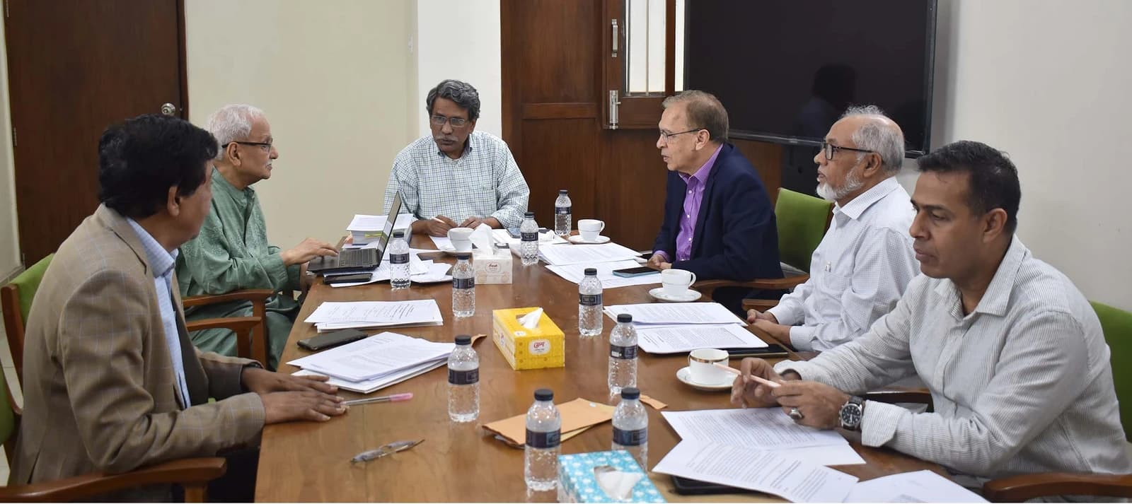Members of the National Consensus Commission meeting at a table with documents and water.