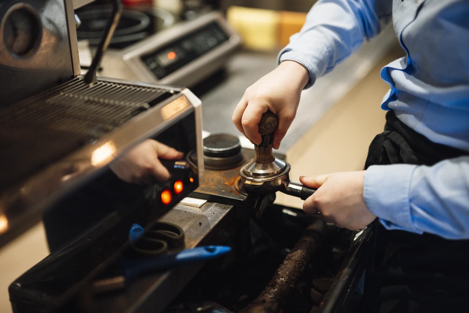 A barista using a tamper to press ground coffee into a portafilter.
