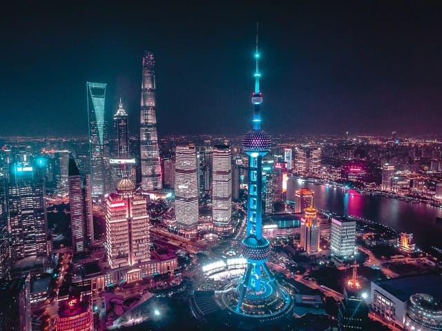 Aerial view of Shanghai's Pudong financial district at night, illuminated skyscrapers.