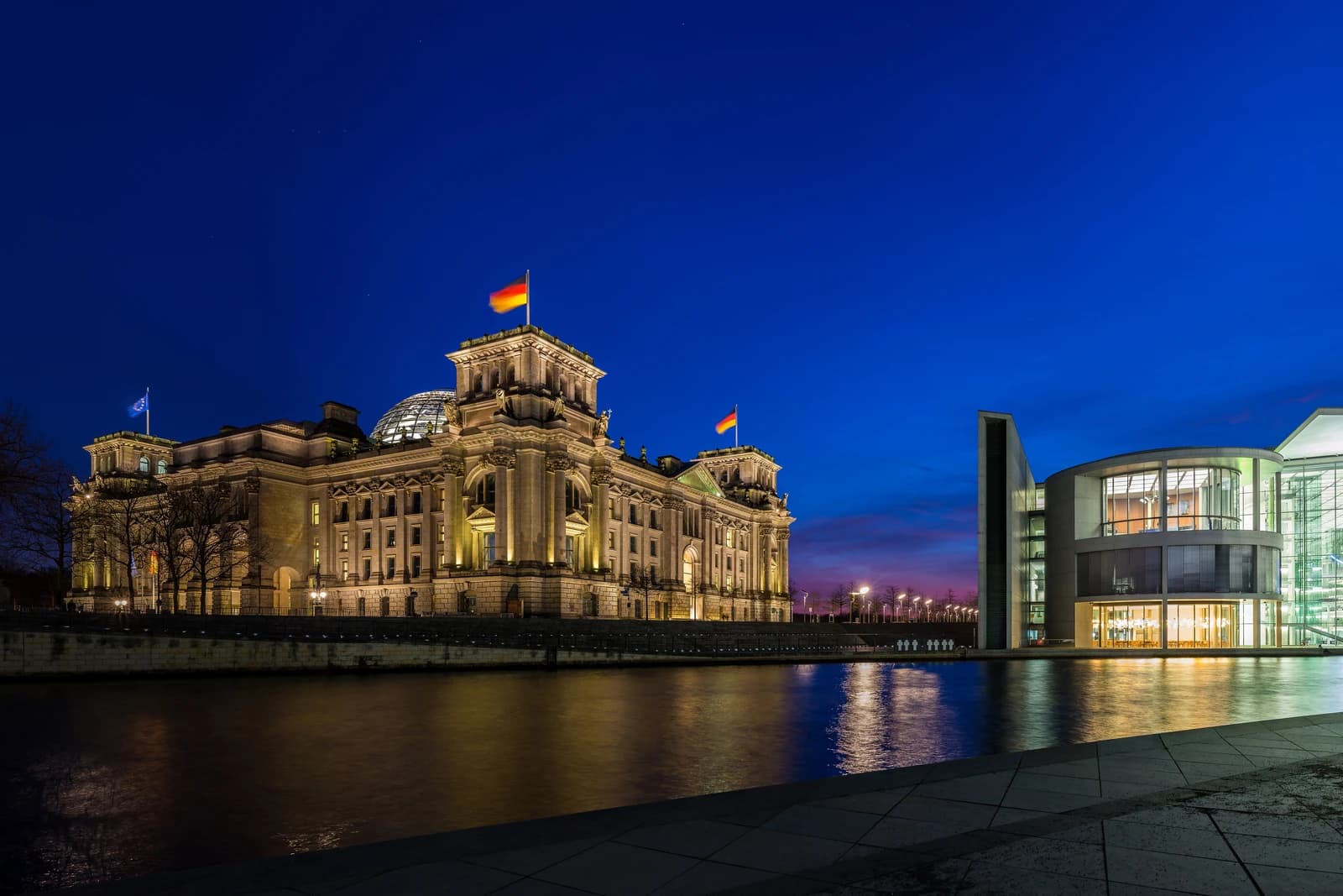 Reichstag Building and Paul Löbe Haus in Berlin, Germany, illuminated at dusk.