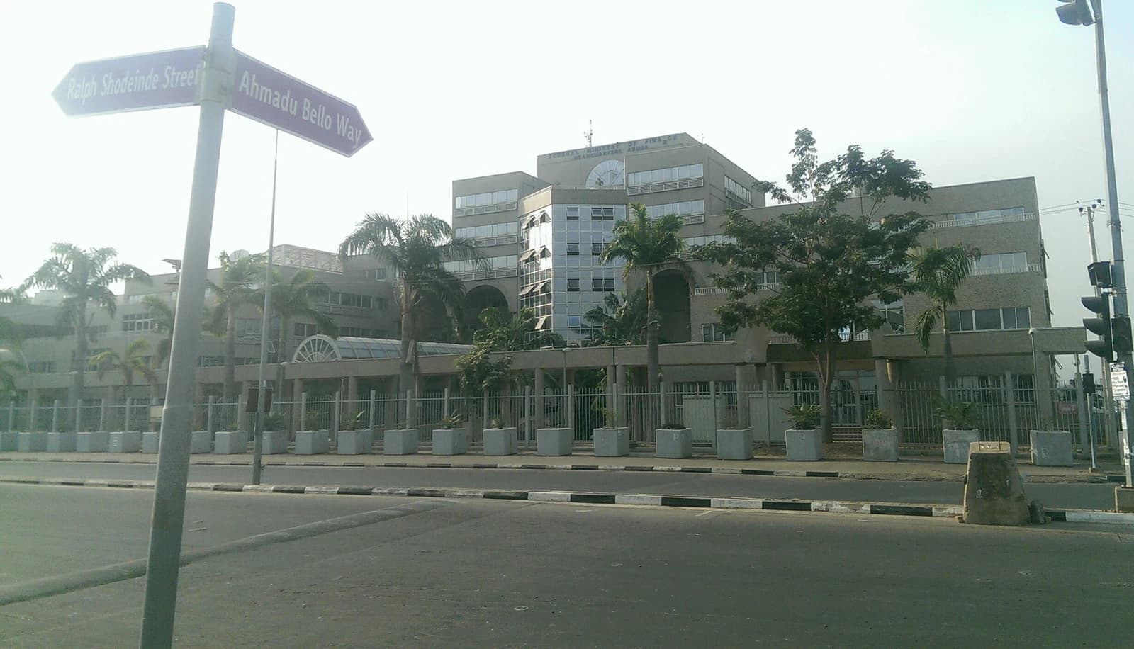 Federal Ministry of Finance headquarters building in Abuja, Nigeria, with street signs in the foreground.