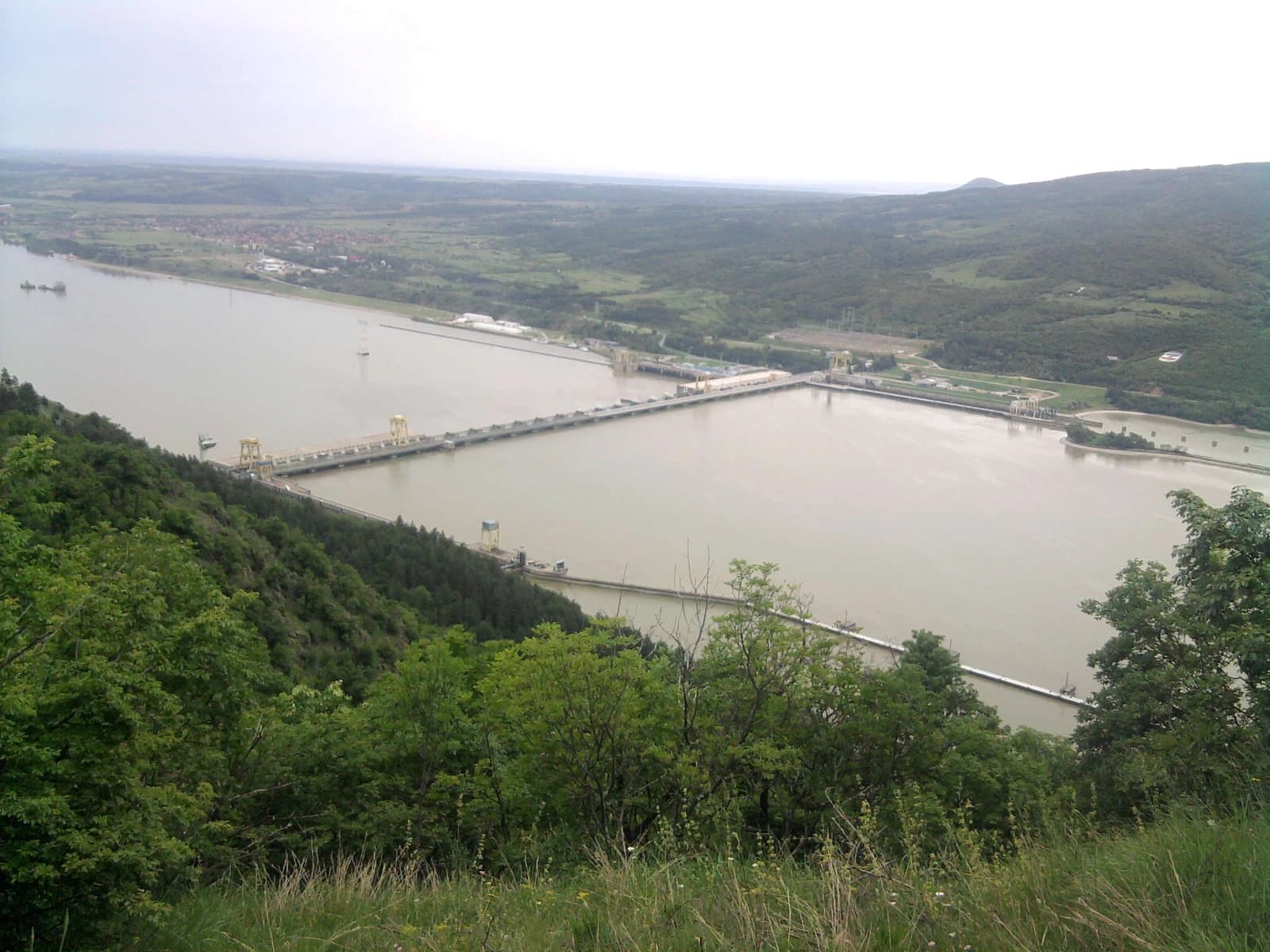 Iron Gate I hydroelectric power station spanning a wide river with forested hills.