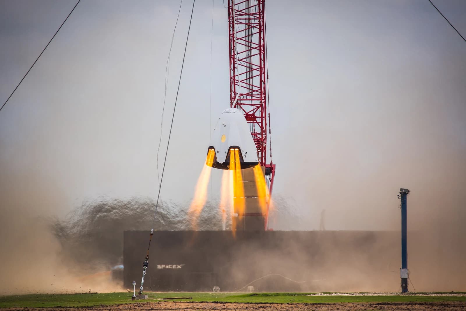 SpaceX Dragon 2 capsule performing a hover test, with four engines firing.