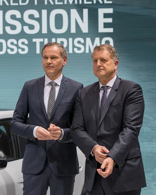 Porsche executives standing in front of a screen displaying "MISSION E CROSS TURISMO".