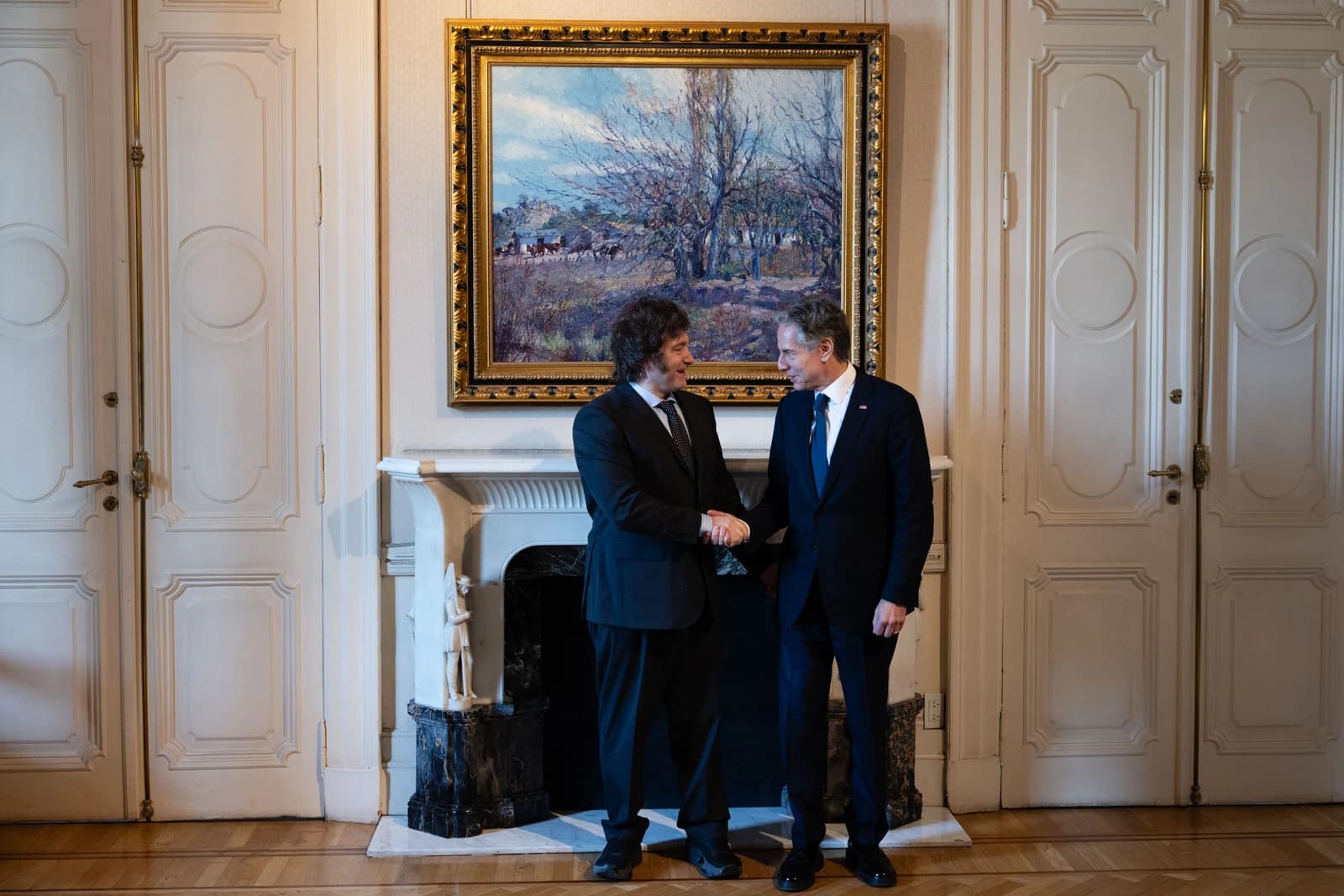 Argentine President Javier Milei shakes hands with US Secretary of State Antony Blinken indoors.
