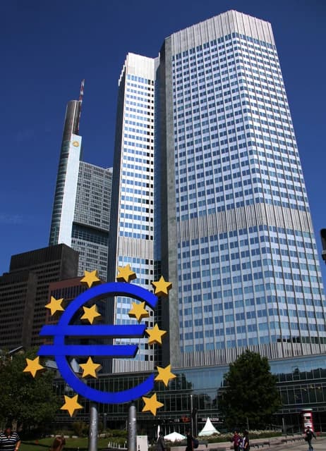 Euro sculpture with gold stars in front of the Eurotower building in Frankfurt.