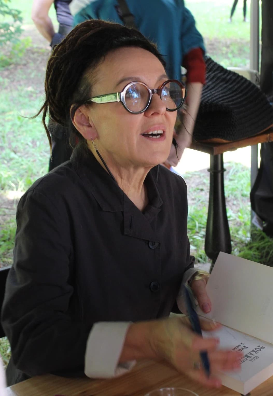 Olga Tokarczuk, Polish writer, signing a book at an outdoor event.