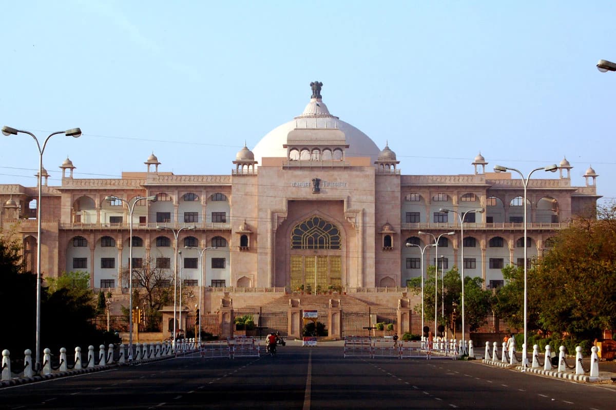 Exterior of the large, domed Rajasthan Assembly building, with a wide road in the foreground.