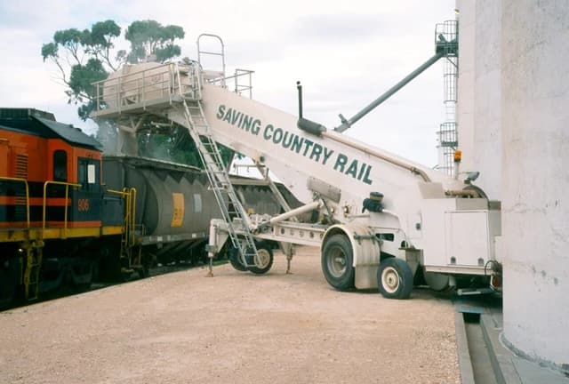 Mobile grain loader transferring grain from a silo into a freight train car.