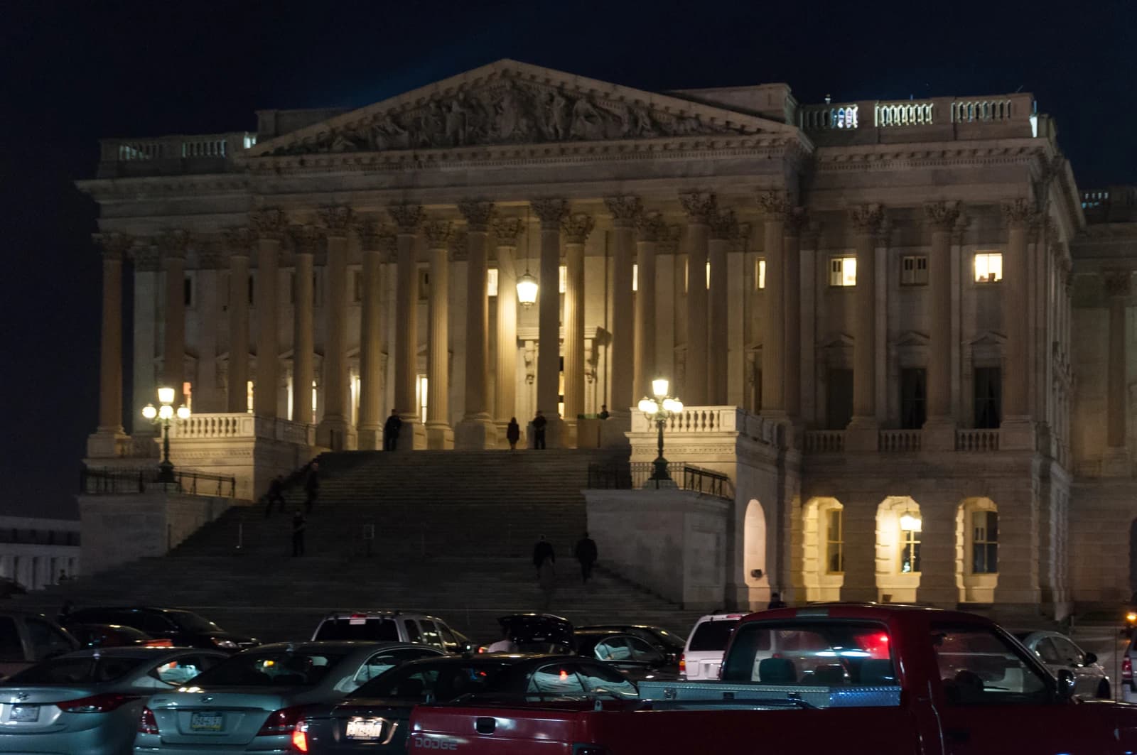 United States Chamber of Representatives building illuminated at night with a parking lot in front.