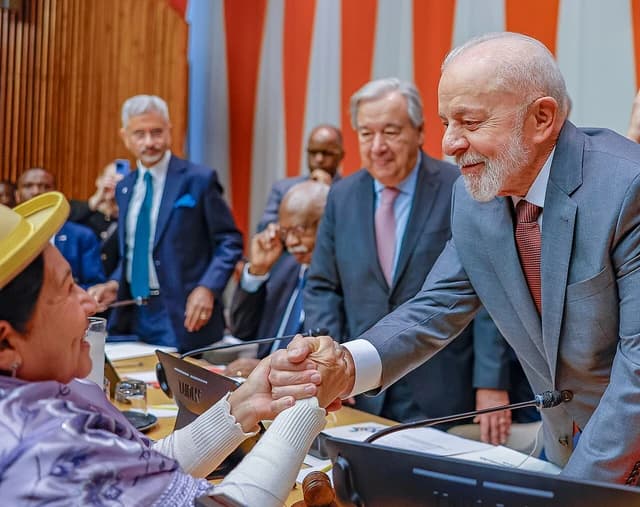 Lula da Silva, President of Brazil, shaking hands with a woman at a G20 meeting.
