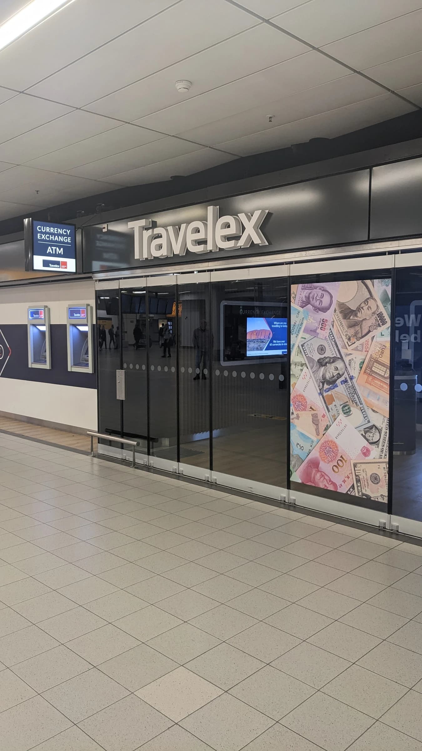 Exterior of a Travelex currency exchange booth with ATMs inside Schiphol Airport.