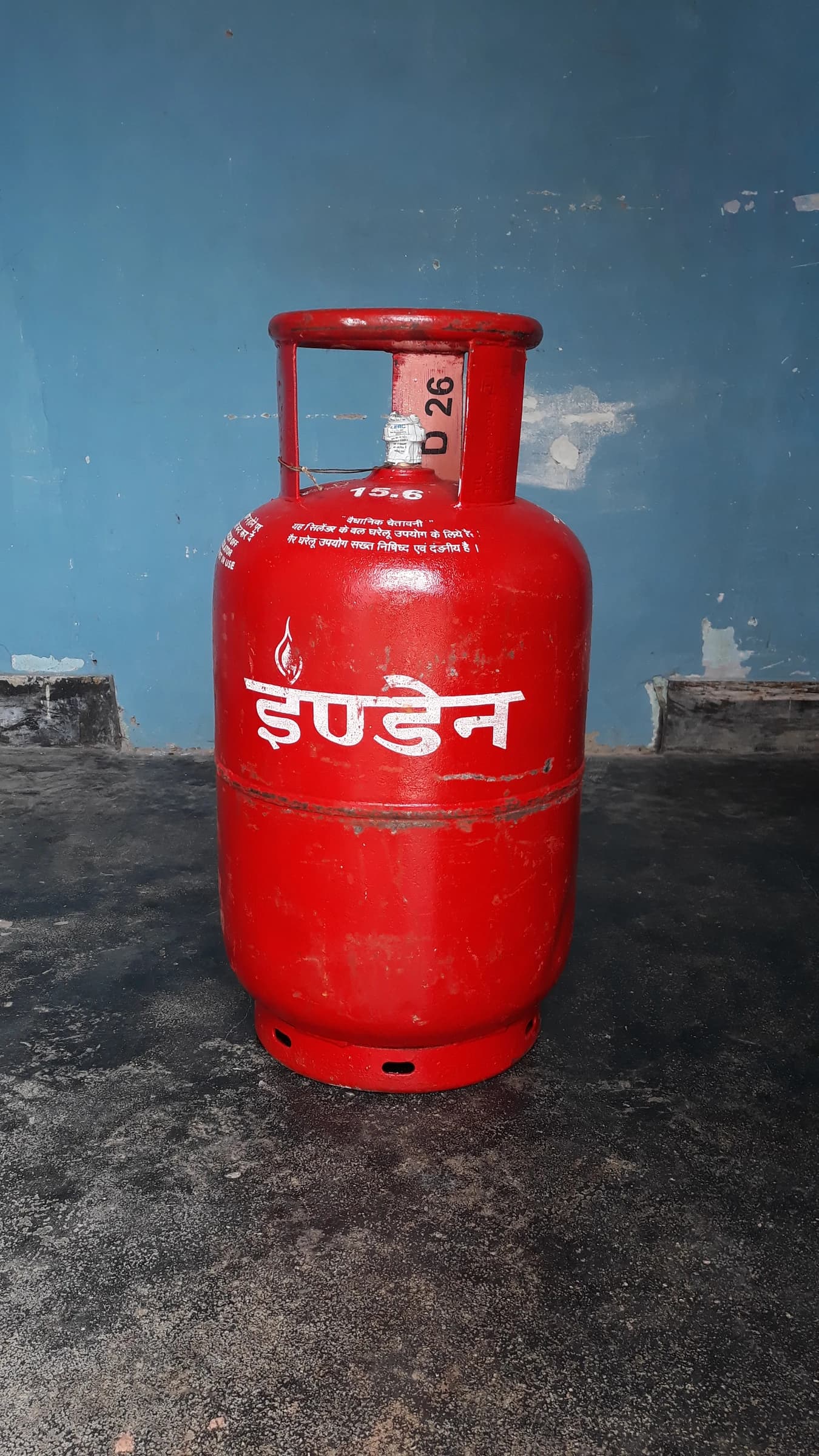 Red Indane LPG gas cylinder with Hindi text on the side.