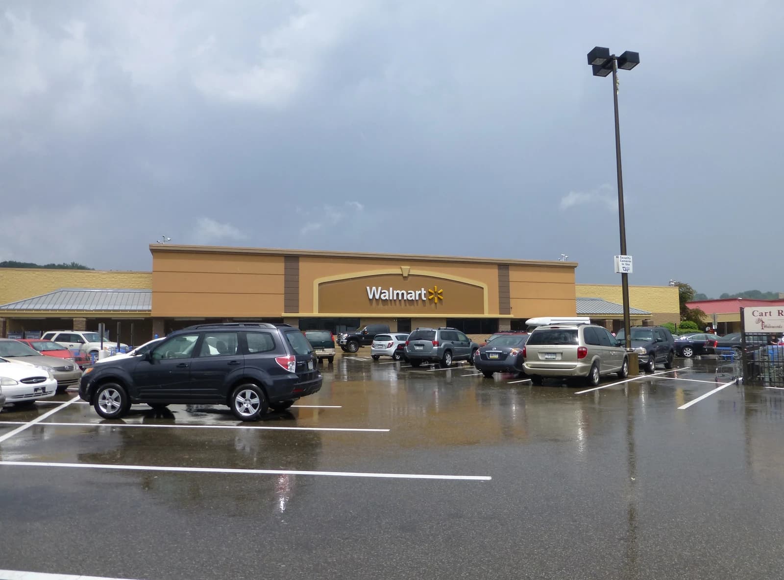 Exterior view of a Walmart store building with a parking lot full of cars in front.