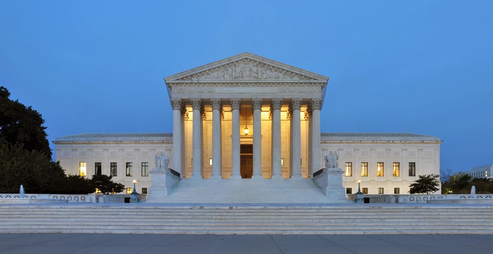 Exterior of the United States Supreme Court Building, illuminated at dusk.
