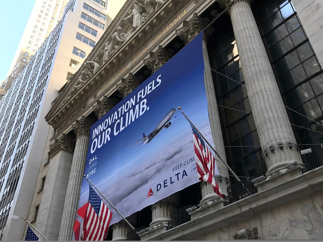 Exterior of the New York Stock Exchange building with a large Delta Airlines banner.